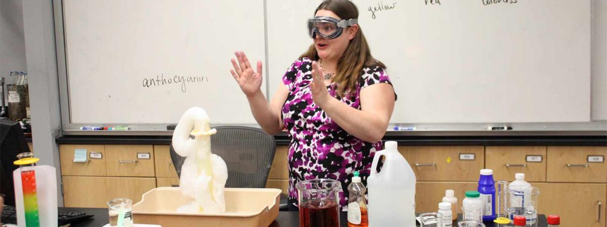Chemistry Program at Minneapolis College student wearing goggles giving a class demonstration in Chemistry at Minneapolis College