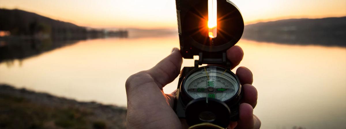 Study Geography at Minneapolis College A compass being held up showing the sun shining through the sighting tab