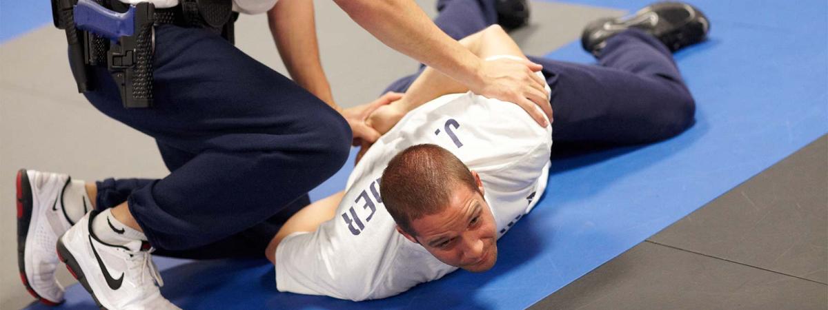 Law Enforcement Program at Minneapolis College Instructor demonstrating proper hold-down technique on student