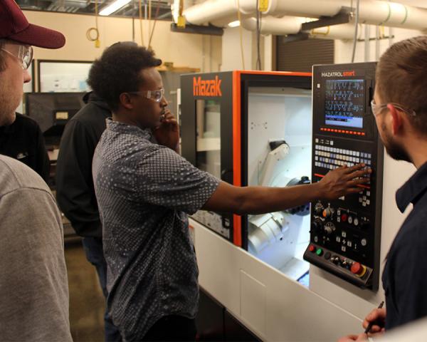 Student operating a computerized machining tool