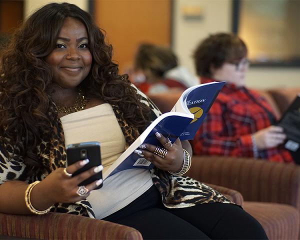 Student sitting with phone and book